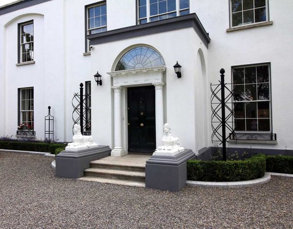 The stately Charleston Rose Obelisk by Classic Garden Elements in front of a Georgian mansion