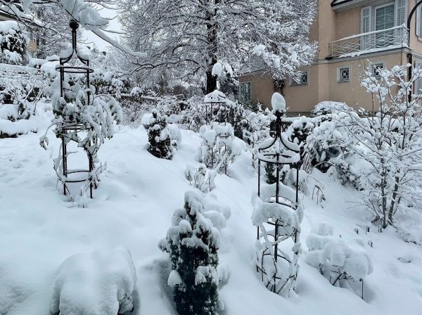Three snow-covered Classic Garden Elements obelisks in a garden in Zurich