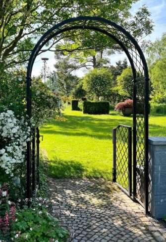 The Portofino Garden Arch with Garden Gate by Classic Garden Elements connects two parts of a garden
