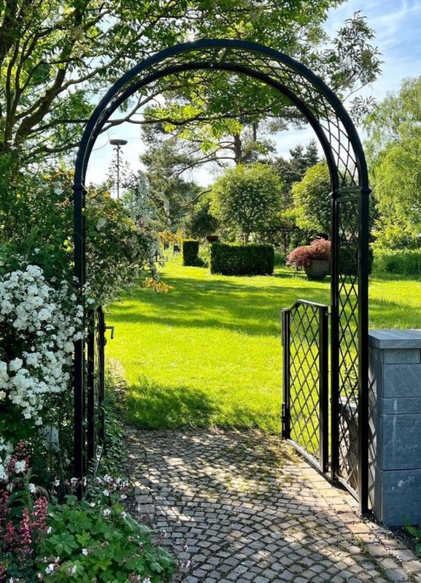 The Portofino Garden Arch with Garden Gate by Classic Garden Elements connects two parts of a garden