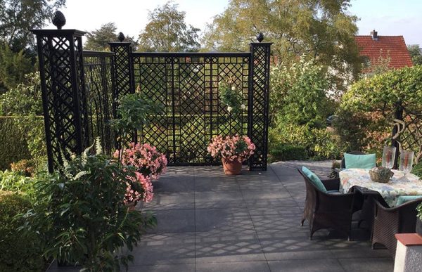 The Wessling Treillage Set by Classic Garden Elements in black, installed at the edge of a patio