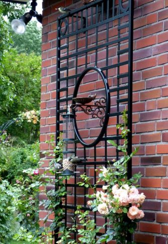 The Knebworth House Metal Wall Trellis in black, mounted on a brick wall