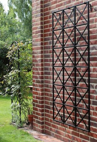 The Ravenna Metal Wall Trellis mounted on a red brick wall
