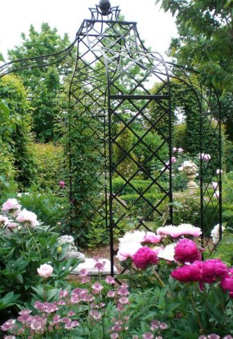 The Kiftsgate Gazebo by Classic Garden Elements surrounded by pink flowers