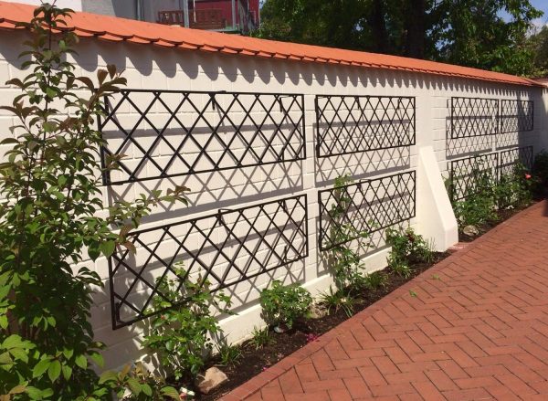 Classic Garden Elements De Rigueur Wall Trellises decorating a long white garden wall