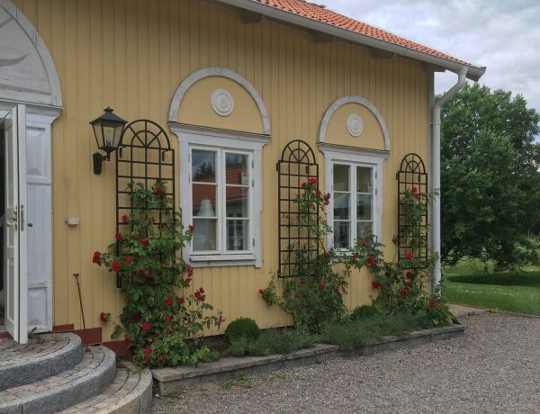 Three black Orangery Wall Trellises by Classic Garden Elements, on a yellow house wall in Sweden