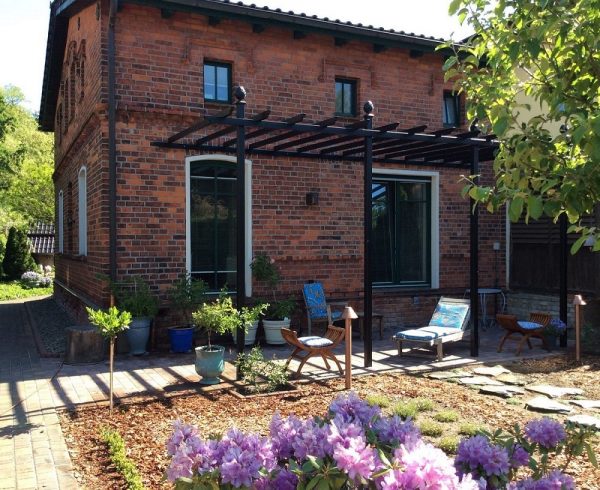 The Piemont Metal Pergola installed against a red-brick house