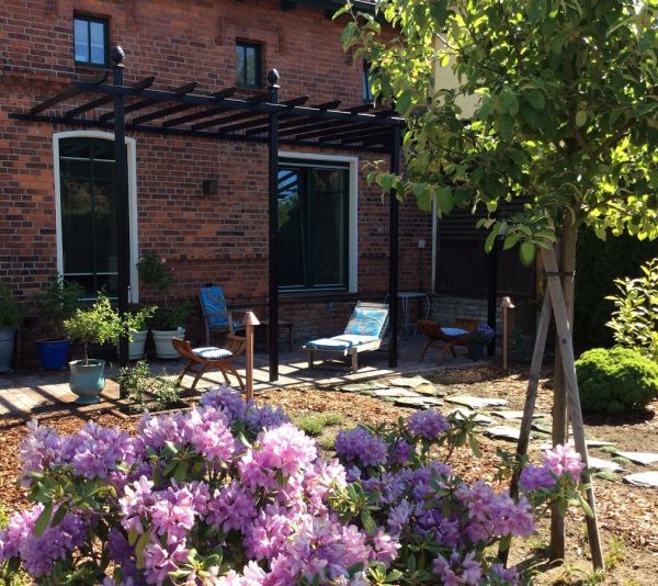 The Piemont Metal Pergola by Classic Garden Elements in the garden of a red-brick house in Spreewald, Brandenburg