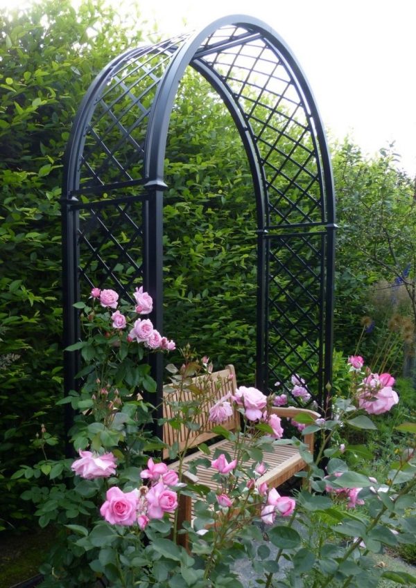 The Portofino Romanesque Garden Arch with a wooden bench and pink roses