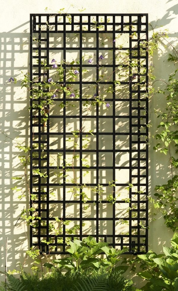 The Poundbury Metal Wall Trellis in black, casting shadows in the sun